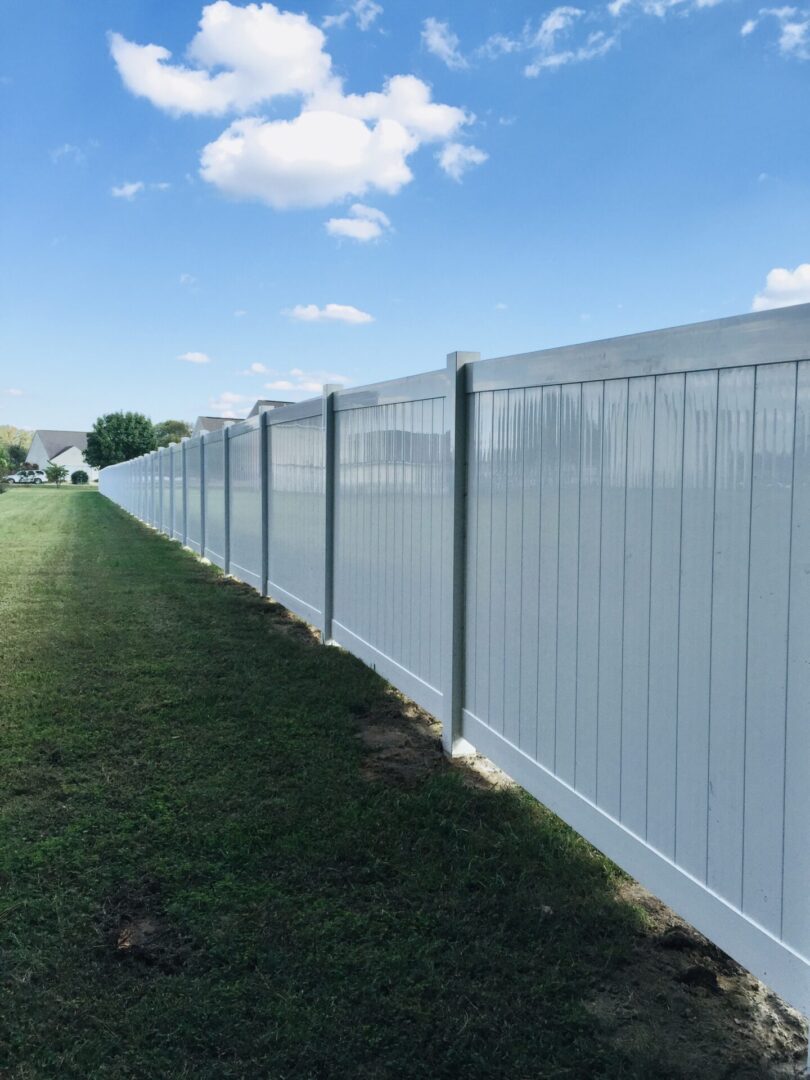 A white fence with grass around it and some trees