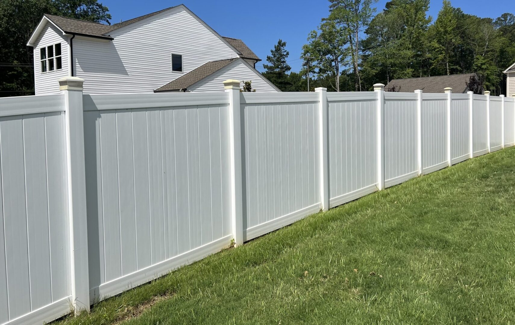 A white fence with trees in the background