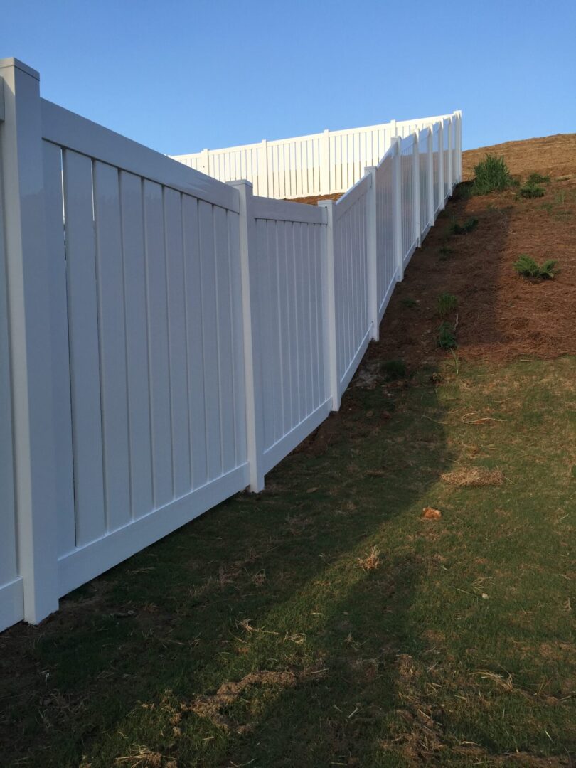 A white fence with grass growing on it