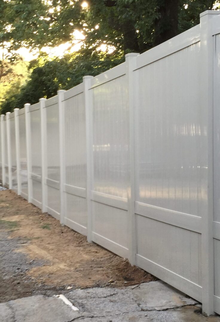 A white fence with trees in the background