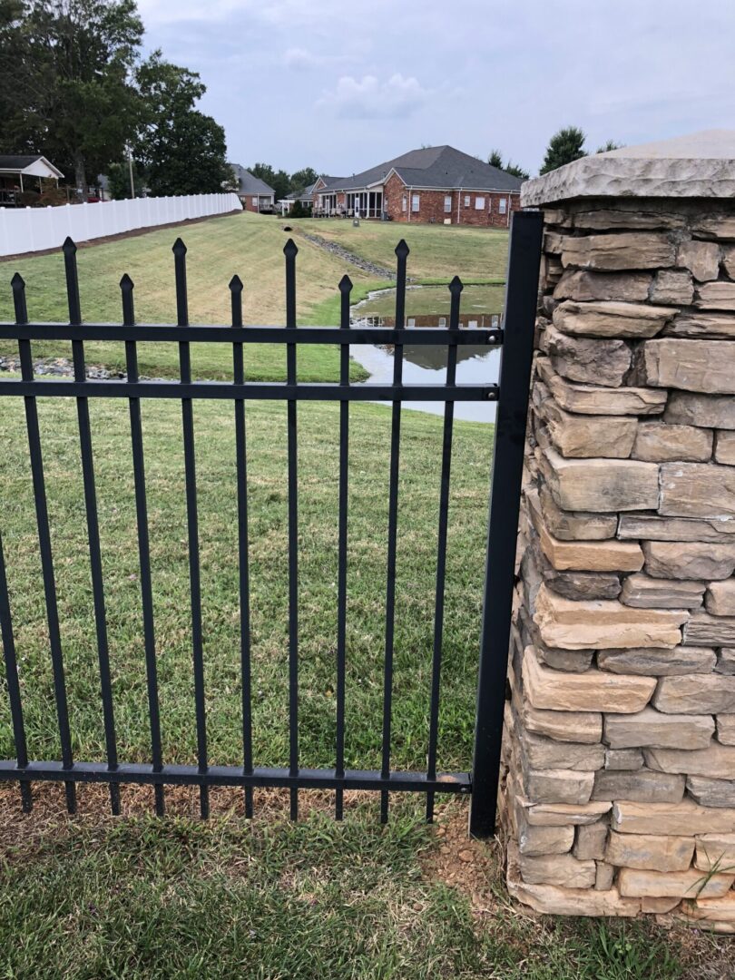 A fence with a stone wall and grass in the background.