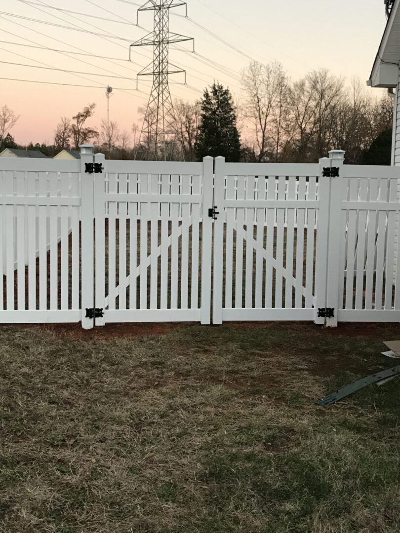 A white fence with two gates open in the middle of it.