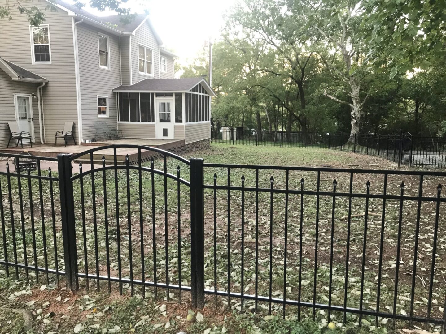 A fence that is in the grass near some trees.