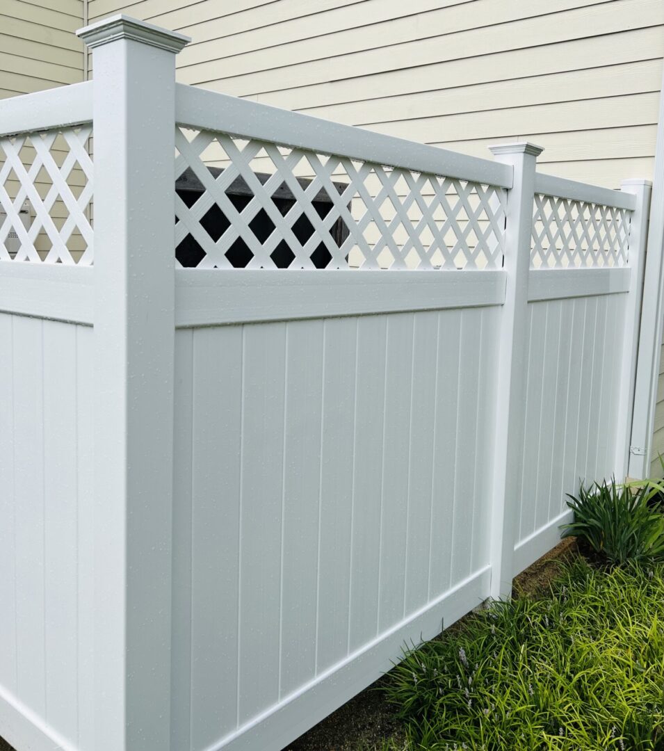 A white fence with a lattice top on the side.