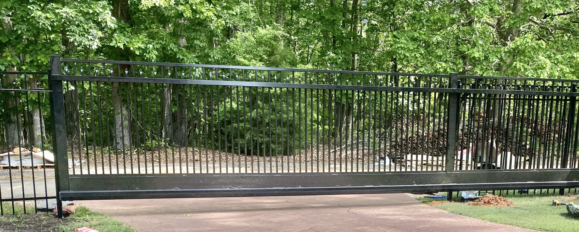 A black metal gate in front of trees.