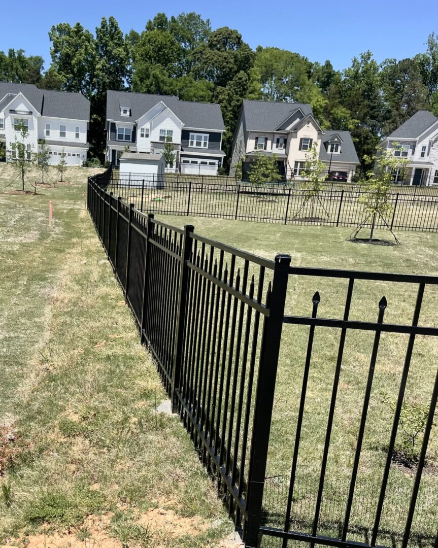 A fence that is in the grass near some houses.