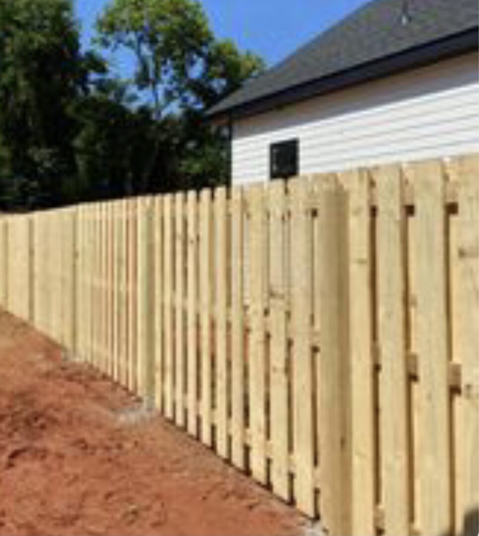 A wooden fence with a house in the background.