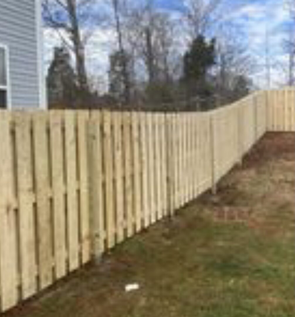 A wooden fence in the middle of a yard.